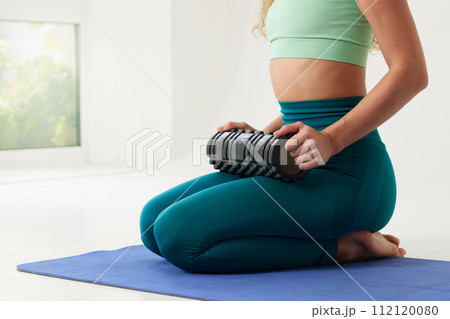 girl massages her back on a roller and does yoga on a white background, massage roller for fitness and yoga, Home training 112120080