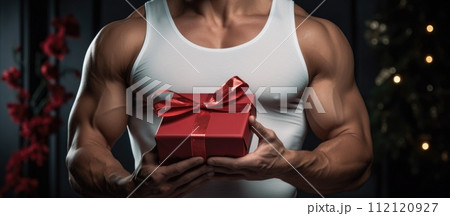 A muscular man holds a gift for a birthday or international women's day gift for a woman on March 8 . Congratulations on your present . 112120927