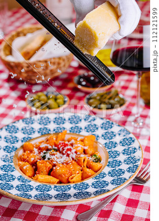 hef grates cheese to the plate with fresh penne pasta 112121599