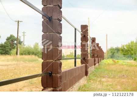 Brown metal profile fence with block posts. Incline construction 112122178