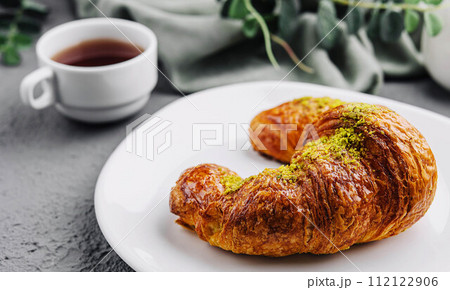 Pistachio Croissant on plate with Tea 112122906