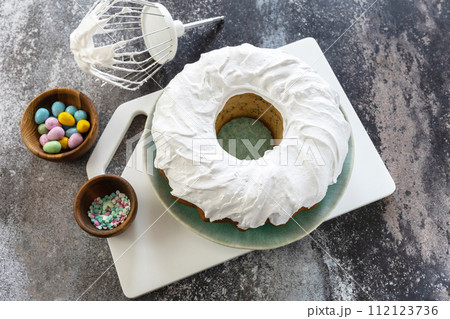 Cooking Glazed easter lemon cake decorated with confectionery and mini chocolate eggs candy on gray stone background, step by step, step 10. 112123736