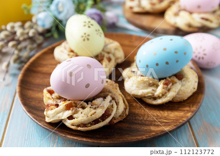 Sweet italian Easter bread rings from puff pastry and dyed eggs on a wooden blue tabletop. 112123772