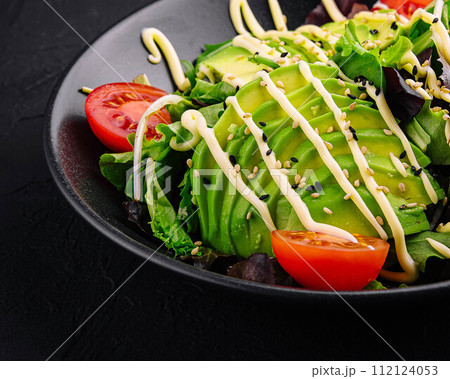 Dietary salad with avocado on a black plate Dietary salad with avocado on a black plate 112124053