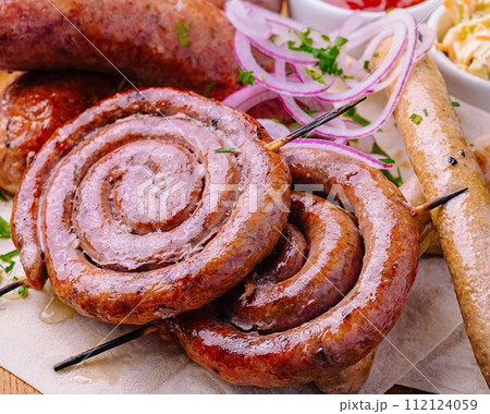 Grilled sausages on a wooden board with sauce Grilled sausages on a wooden board with sauce 112124059
