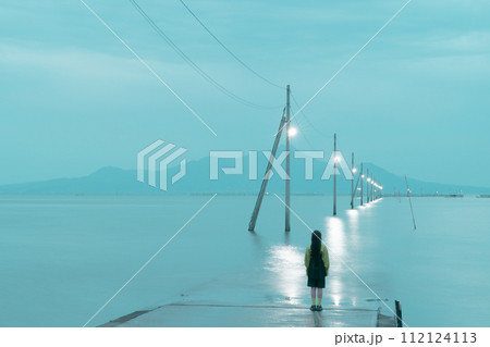 長部田海床路の海へと続く電柱(夕方)と後ろ姿の女性 長部田海床路の海へと続く電柱(夕方)と後ろ姿の女性 112124113