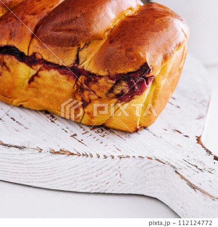 Delicious baked bun with cherry on white wood Delicious baked bun with cherry on white wood 112124772