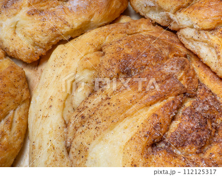 Wicker bun with cinnamon and sugar. Bread product of an unusual shape. Homemade baking. Buns with a ruddy crust. 112125317