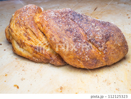 Wicker bun with cinnamon and sugar. Bread product of an unusual shape. Homemade baking. Buns with a ruddy crust. 112125323
