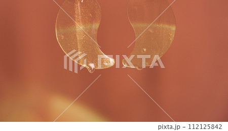 Transparent eye patches with serum hanging against a red background 112125842