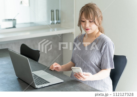 スマホ・ノートパソコンで妊娠日記・妊娠記録・母子手帳アプリを使う若い妊婦の女性 スマホ・ノートパソコンで妊娠日記・妊娠記録・母子手帳アプリを使う若い妊婦の女性 112127328