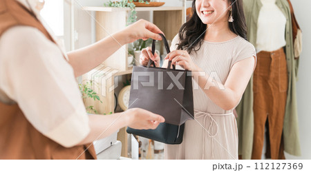 アパレルショップ・雑貨屋のレジで商品を受け取る女性客 112127369