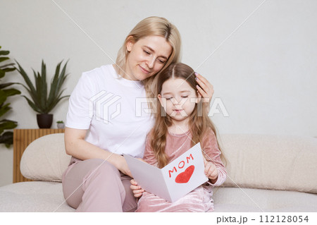 Happy mother's day. Child daughter congratulating her mother and giving her postcard. 112128054