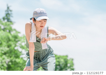 公園でトレーニング・ジョギングのインターバル中にスマートウォッチを確認する若いアジア人女性 112128177