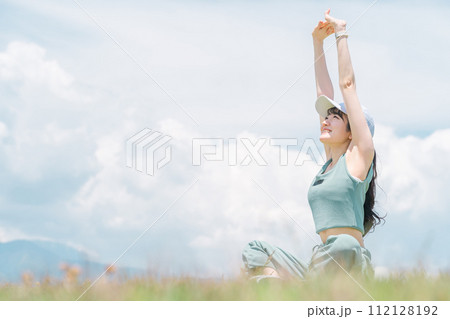 公園でヨガ・ストレッチ・伸び・深呼吸・リフレッシュをする女性 112128192