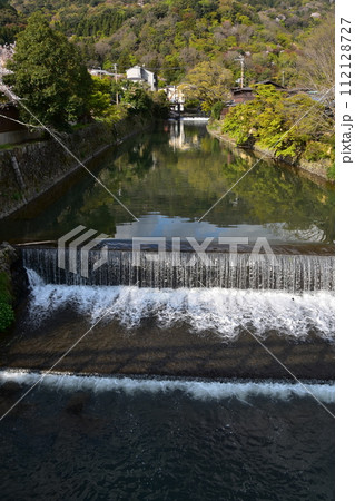 日本の春の京都　嵐山周辺の街並み　観光名所の桂川と満開の桜と美しい新緑　川沿いの古い住居 112128727