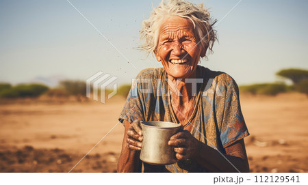 Poor, beggarly, hungry dark-skinned old woman from Africa, thirsty to drink water. 112129541