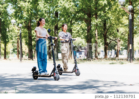 電動キックボードで爽やかに走る若い女性 112130701