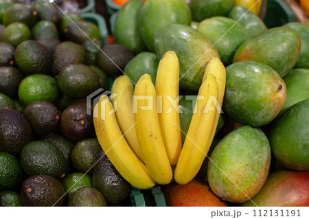 A branch of ripe bananas and avocados for sale in the store. 112131191