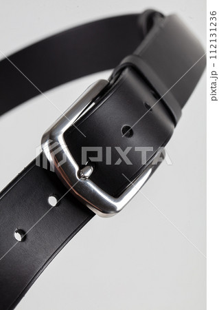 Part of a black leather classic belt with a buckle on a gray background. Part of a black leather classic belt with a buckle on a gray background. 112131236