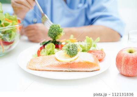 Asian elderly woman patient eating salmon stake and vegetable salad for healthy food in hospital. Asian elderly woman patient eating salmon stake and vegetable salad for healthy food in hospital. 112131836