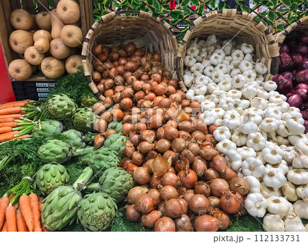Garlic, white onions, red onions and artichokes sold in wicker baskets in supermarkets 112133731