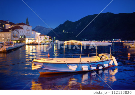 View of ancient picturesque city of Perast. Old medieval little town with red roofs and mountains on background of famous Kotor bay of Adriatic sea at blue hour. Travel in Montenegro. 112133820