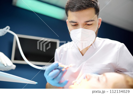 Dentist and patient at modern medical center. Doctor treats a young woman teeth in hospital. Practitioner examines the patient before orthodontists or prosthetics treatment. Dentist and patient at modern medical center. Doctor treats a young woman teeth in hospital. Practitioner examines the patient before orthodontists or prosthetics treatment. 112134029