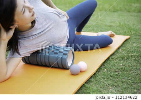 ヨガウェアを着て芝生の上で寝転ぶ女性 112134622