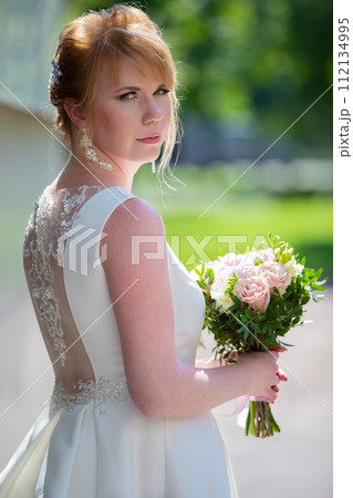 Beautiful bride in a wedding dress with a bouquet 112134995