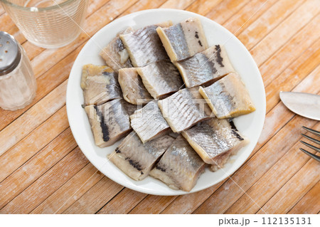 Pieces of pickled herring on a plate 112135131