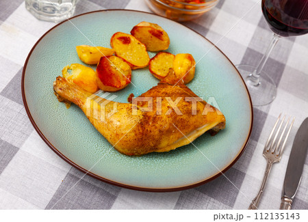 Barbecued chicken leg with boiled potatoes closeup on plate 112135143