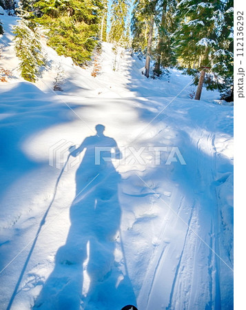A person is skiing down a snowy hill with trees in the background A person is skiing down a snowy hill with trees in the background 112136292