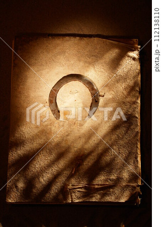 A worn leather bound book with a horse shoe on the cover 112138110