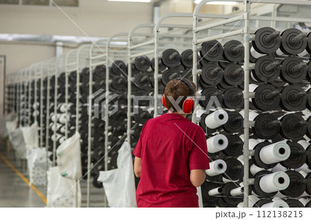 A worker controls the operation of equipment with spools of polypropylene threads. A worker controls the operation of equipment with spools of polypropylene threads. 112138215