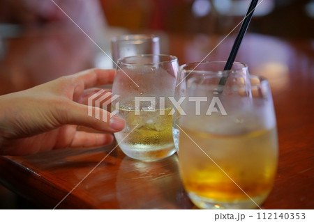 バーでウイスキーグラスを持つ手元 バーでウイスキーグラスを持つ手元 112140353