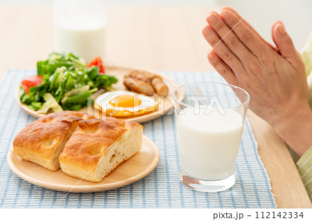 牛乳とパンの朝食を食べる女性の手元 112142334
