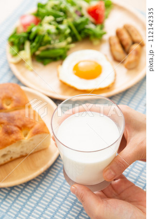 牛乳とパンの朝食を食べる女性の手元 112142335