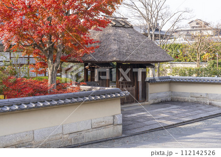 秋の京都　高台寺　春光院　紅葉に包まれた茅葺き屋根の門 112142526
