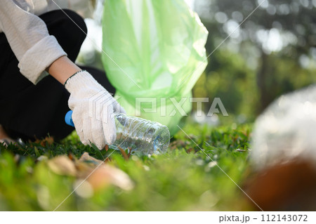 Closeup young woman hand collecting plastic bottles, cleaning up nature. Charity and ecology concept Closeup young woman hand collecting plastic bottles, cleaning up nature. Charity and ecology concept 112143072