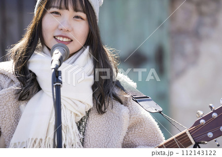 冬に弾き語りで路上ライブをする若い女性 冬に弾き語りで路上ライブをする若い女性 112143122