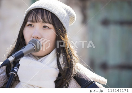 冬に弾き語りで路上ライブをする若い女性 112143171