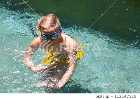 Teenage boy playing in swimming pool. Teenage boy playing in swimming pool. 112147519