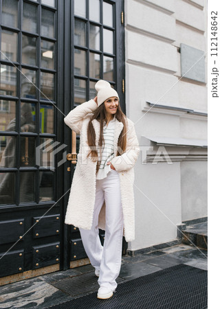 Young woman in stylish light-colored clothes strolls through the streets of the city Young woman in stylish light-colored clothes strolls through the streets of the city 112148642