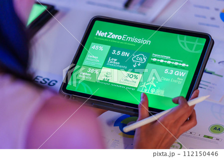 woman  analysis  net zero emission data on tablet screen in office  at night 112150446
