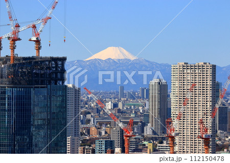 A snow covered Mt Fuji, Fuji-san, as seen from minatoku in central tokyo framed by cranes making high rise buildings 112150478
