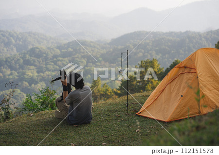 landscape and travel concept with solo freelancer man relax and play with cat and see sunset with layer of mountain 112151578