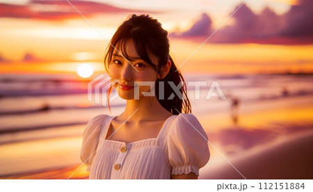 夕焼けの海岸を歩く女性 112151884