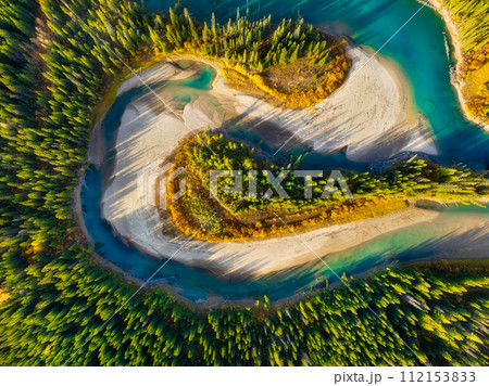 A drone view of the river in the forest. An aerial view of an forest. Winding river among the trees. 112153833