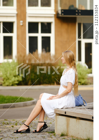 Side view at young woman sitting in profile on a bench Side view at young woman sitting in profile on a bench 112153834